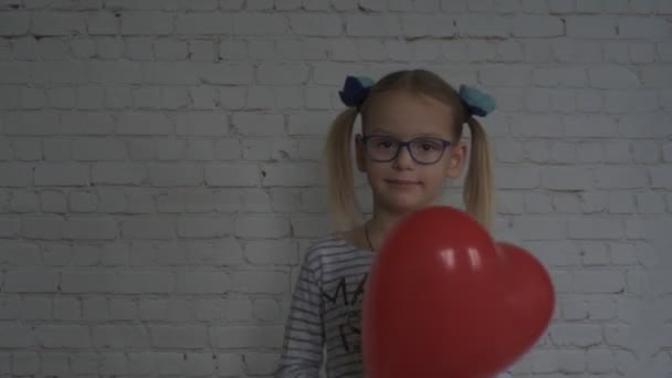 Klein meisje met rode hartvormige ballon, Valentijnsdag achtergrond — Stockvideo