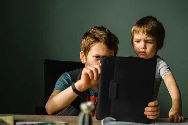 Menino júnior com seu irmão jogando tablet em casa, crescendo com tecnologia — Fotografia de Stock