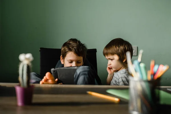 Junior jongen met zijn broer spelen tablet thuis, opgroeien met technologie — Stockfoto
