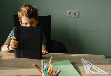 İlkokul öğrencisi evde tablet kullanıyor, teknolojiyle büyüyor.