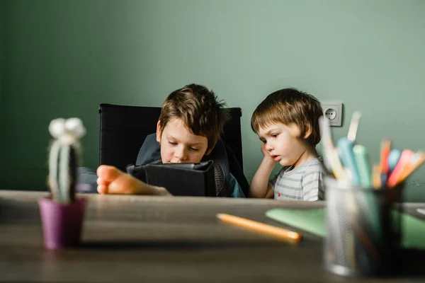 Menino júnior com seu irmão jogando tablet em casa, crescendo com tecnologia — Fotografia de Stock