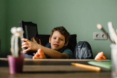 Evde tablet kullanan, teknolojiyle büyüyen gülümseyen çocuk.