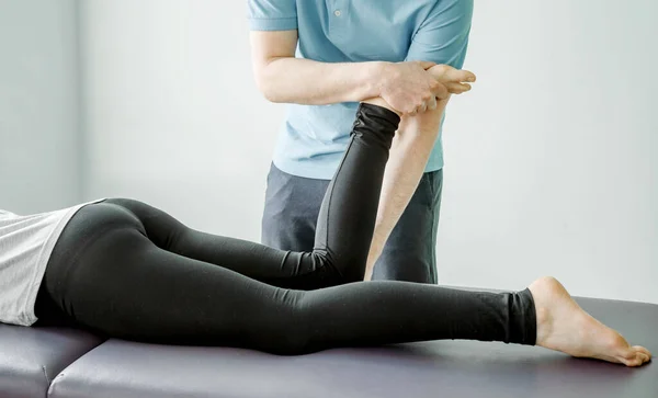 Physical therapy treatments for piriformis syndrome, physical therapist stretches female patient\'s buttocks muscle, post-isometric relaxation