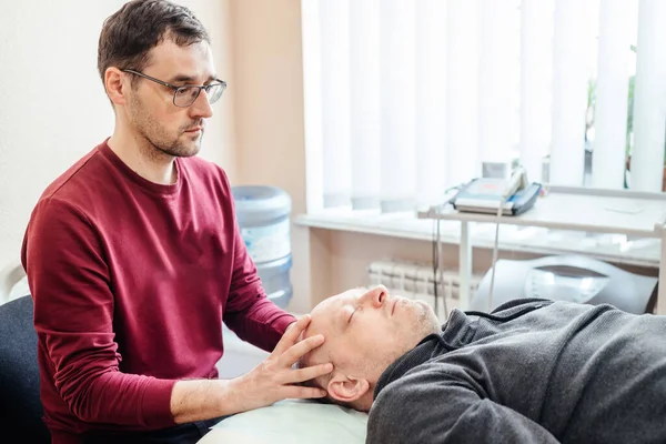 Craniosacral therapy practitioner giving a male patient CST ostheopatic treatment, osteopathy and manual therapy — Stock Photo, Image