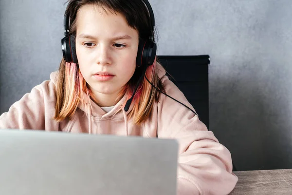 Uma menina usando fones de ouvido e usando seu laptop enquanto estudava online, e-learning e conceito de educação on-line — Fotografia de Stock