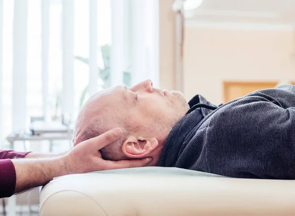 Male patient receiving cranial sacral therapy, lying on the massage table in CST osteopathic clinic, osteopathy and manual therapy — Stock Photo, Image