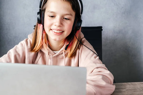 Menina sorridente usando fones de ouvido e usando seu laptop enquanto estuda on-line, e-learning e conceito de educação on-line — Fotografia de Stock