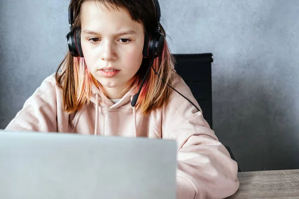 Tiener meisje doet haar huiswerk online en het luisteren naar koptelefoon. — Stockfoto