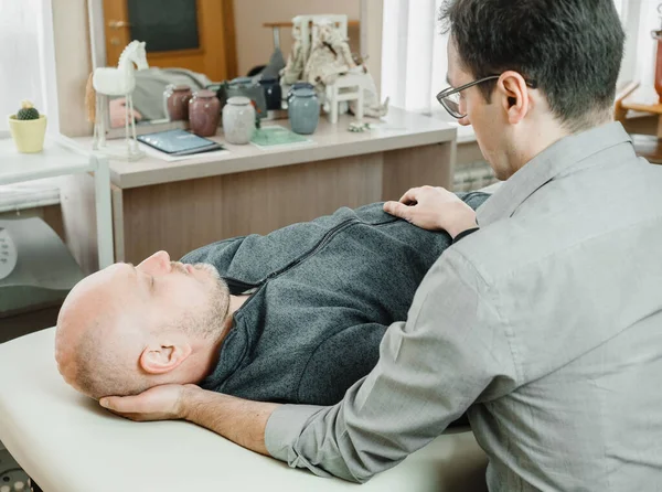 Ostheopatic treatment of a patient using CST gentle hands-on technique, central nervous system tension relieve — Stock Photo, Image