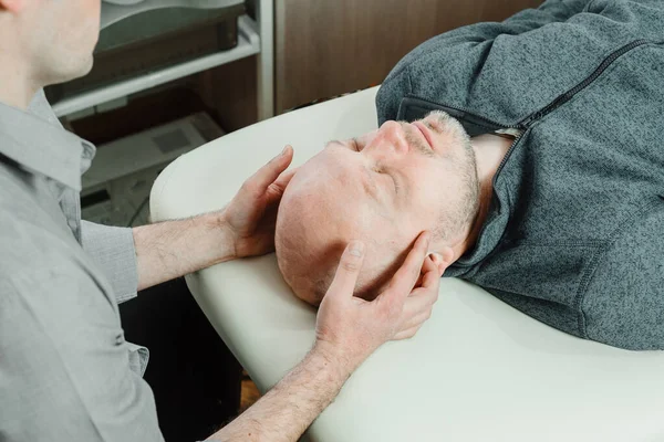 CST tekniğini kullanan bir hastanın osteopatik tedavisi. Merkezi sinir sistemi gerilimi acıyı azaltmak ve sağlık ve bağışıklık sistemini güçlendirmek için kullanılır.