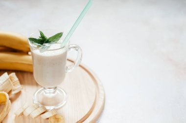Süt muzlu milkshake latte bardakta nane yaprağı ile süslenmiş ve arka planda fotokopi alanı ve yaz içecekleriyle dolu.