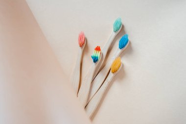 Hafif pastel arka planda renkli çevre dostu bambu diş fırçaları, sıfır atık konseptli diş bakımı, sürdürülebilir yaşam tarzı