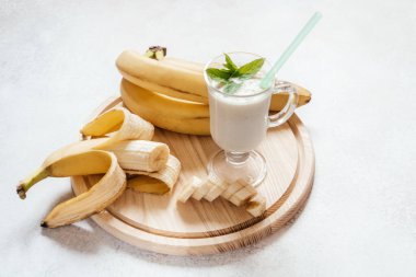 Süt muzlu milkshake latte bardakta nane yaprağı ile süslenmiş ve arka planda fotokopi alanı ve yaz içecekleriyle dolu.