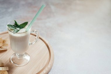 Süt muzlu milkshake latte bardakta nane yaprağı ile süslenmiş ve arka planda fotokopi alanı ve yaz içecekleriyle dolu.