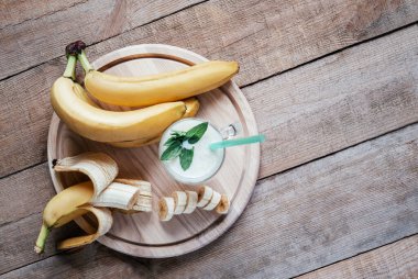 Muzlu kokteyl ya da milkshake ile yaz beşiği, siyah ahşap masada bir bardakta nane yaprakları ve saman.