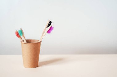 Kağıt bardakta farklı renklerde çevre dostu bambu diş fırçaları, sıfır atık kavramı, sürdürülebilir yaşam tarzı