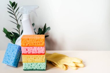 Renkli temizlik süngerleri, beyaz serpinti şişesi ve sarı lastik eldivenler. Temizlik malzemeleri ve temizlik hizmeti konsepti