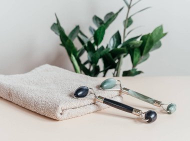 Havlu ve serum şişesinde Jade Guasha masaj ruloları, SPA rahatlama, yüz ve cilt bakımı konsepti