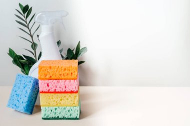 Renkli temizlik süngerleri, beyaz serpinti şişesi ve sarı lastik eldivenler. Temizlik malzemeleri ve temizlik servisi.
