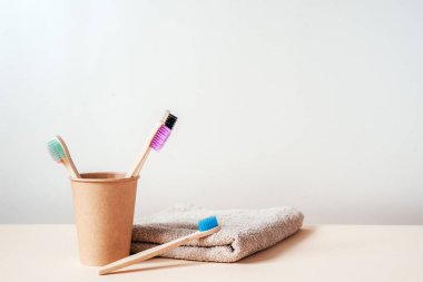 Kağıt bardakta farklı renklerde çevre dostu bambu diş fırçaları, sıfır atık kavramı, sürdürülebilir yaşam tarzı
