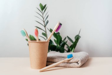 Kağıt bardakta farklı renklerde çevre dostu bambu diş fırçaları, sıfır atık kavramı, sürdürülebilir yaşam tarzı