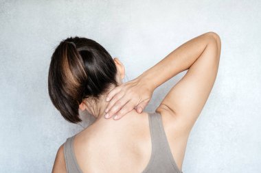 Boynuna eliyle dokunan bir kadın, boyun ağrısı, boyun ağrısı egzersizleri.