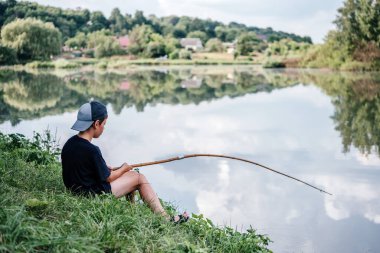 Gölde olta ve balık tutan bir çocuk, çocuklar için yaz aktiviteleri ve hobiler