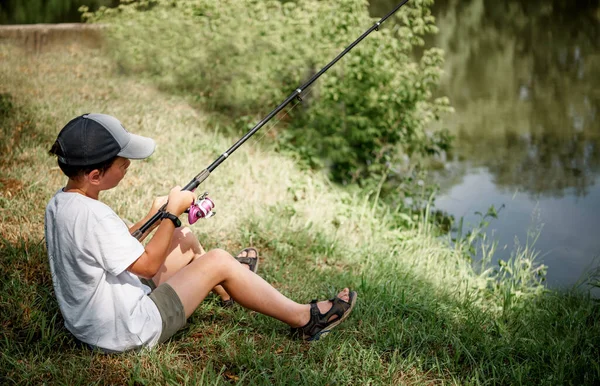 Мальчик держит удочку и рыбалку в озере, летние развлечения и увлечения для детей — стоковое фото