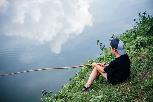 Un niño sosteniendo una caña de pescar y la pesca en el lago, actividades de verano y pasatiempos para los niños — Foto de Stock