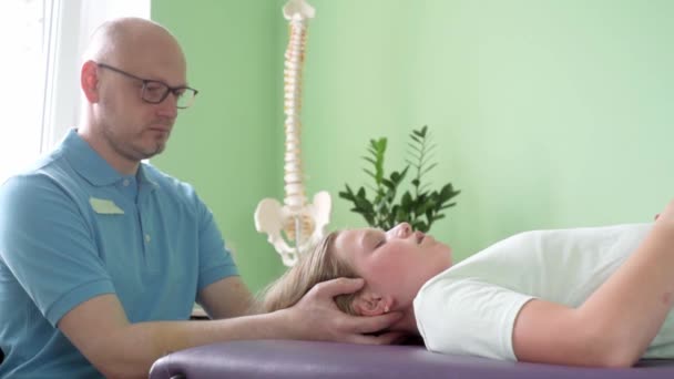 Uma menina que recebe tratamento CST por praticante de osteopata usando a técnica hands-on suave, tensão do sistema nervoso central aliviar — Vídeo de Stock