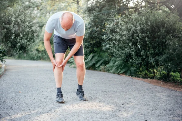 Male runner holding his knee and suffering from runners knee injury