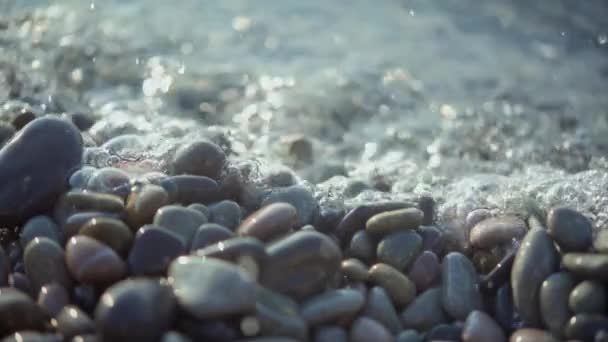 Kiezelstrand met de ochtendzon sprankelend in de oceaan — Stockvideo