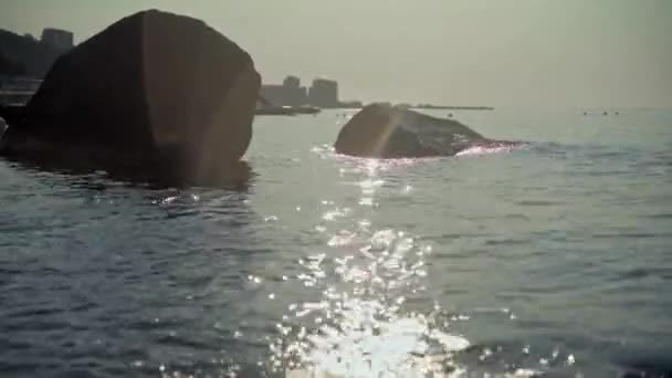 Glittrande lätt stig över havsytan och stora klippor i havet — Stockvideo