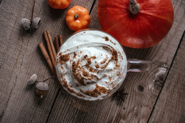 Autumn pumpkin spice hot drink on wooden background top view, autumn vegan latte with spices, cinnamon, and stars of anise