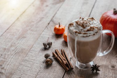 Baharatlı latte, çırpılmış krema ve tarçınlı ahşap arka plan, baharatlı sonbahar vegan latte, tarçın ve anason yıldızları.