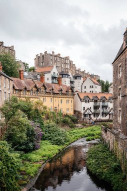 Edinburgh, İskoçya 'daki tarihi dekan köyünde renkli evler, geleneksel mimari ve yemyeşil bir vadide akan Leith Suyu..