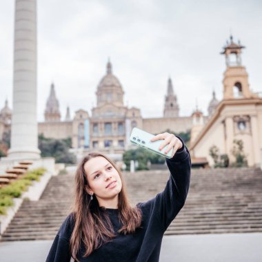 Barcelona 'daki Katalonya Ulusal Sanat Müzesi önünde akıllı telefonuyla selfie çeken genç bir kadın, İspanya' da seyahat, gençlik yaşam tarzı ve kentsel turizmi ön plana çıkarıyor.