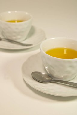 Gövdelerinde sarı sıvı bulunan iki beyaz bardak.