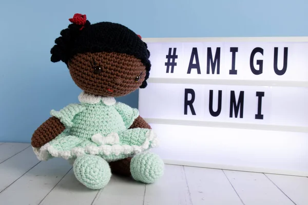 Tığ işi oyuncak bebek ışıklı tabelanın yanında oturuyor.