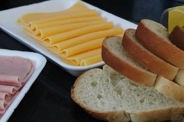 Peynir ve jambonun yanında dilimlenmiş ekmek.