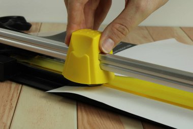 Sarı kağıt kesiciyle beyaz kağıt kesiliyor.