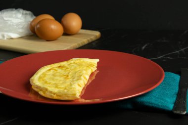 Kırmızı tabakta yarısı yenmiş omlet.