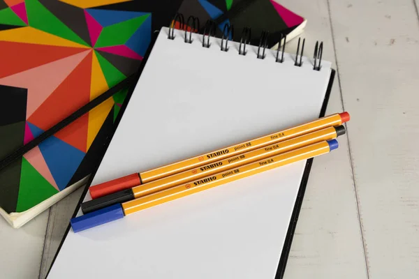 Renkli defterlerin yanında duran boş not defteri