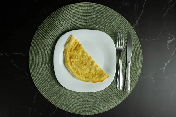 Beyaz kare tabakta duran altın omlet.