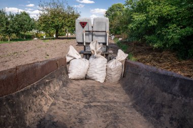 Küçük bir traktör, bir tarlada römork ve prensipte küçük bir mahsul..