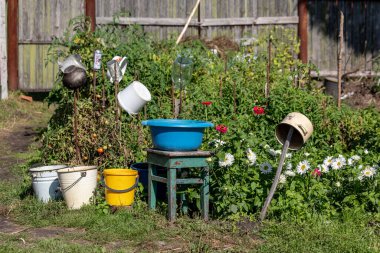 Yazın yeşil arka planda kovalar ve eski tabaklar. Köylülerin kırsal yaşamı..