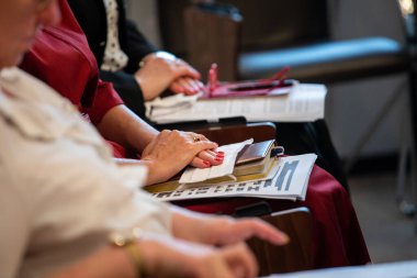 Toplantıda ya da konferansta erkekler ellerinde tükenmez kalemle sandalyeye otururlar..