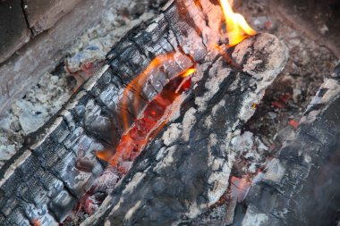 Kırmızı renkte parlayan közler, soyut arka plan. Yanan odun ateşinin sıcak közleri. Yakacak odun ızgarada yanıyor. Doku ateş közleri.
