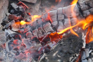 Kırmızı renkte parlayan közler, soyut arka plan. Yanan odun ateşinin sıcak közleri. Yakacak odun ızgarada yanıyor. Doku ateş közleri.