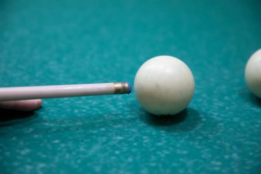 Bir adamın eli beyaz bir bilardo topuna ıstakayla vuruyor.